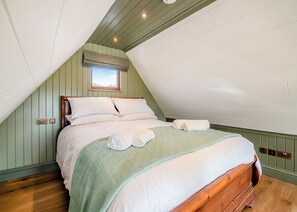 A bedroom with a sloped ceiling, a bed with white linens, a green patterned throw, and a window with a view. - 1 bedroom accommodation in Ripponden (Ripponden)