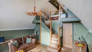 A loft-style living space with a staircase, a sofa, a wooden table, and a chandelier. - 1 bedroom accommodation in Ripponden (Ripponden)