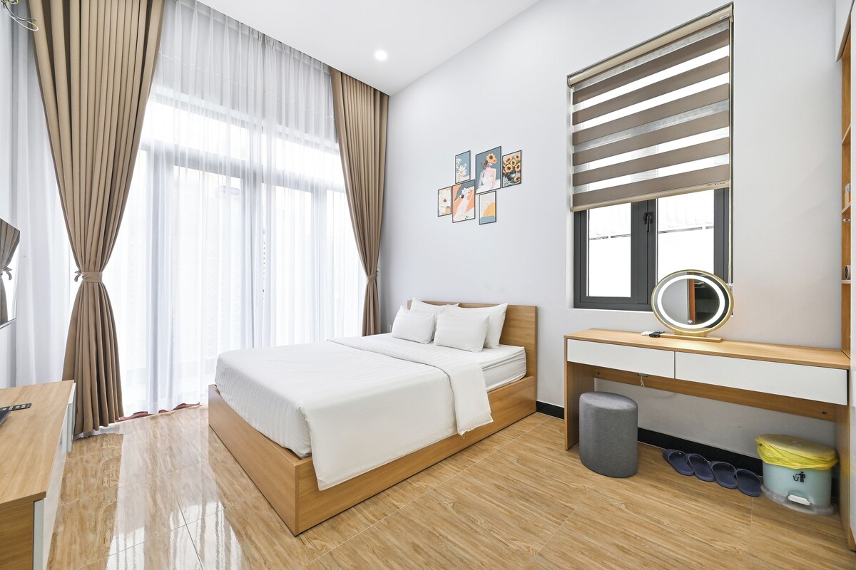 Habitación de hotel con cama, mesita de noche, escritorio y ventana con cortinas.
