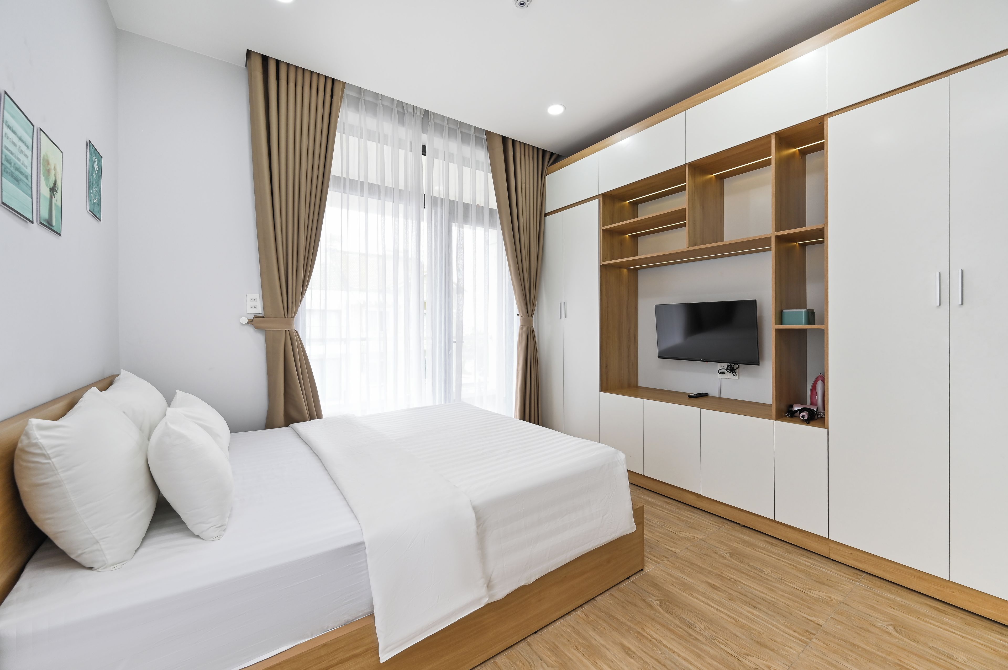 A modern bedroom with a bed, a TV, and built-in wooden shelving.