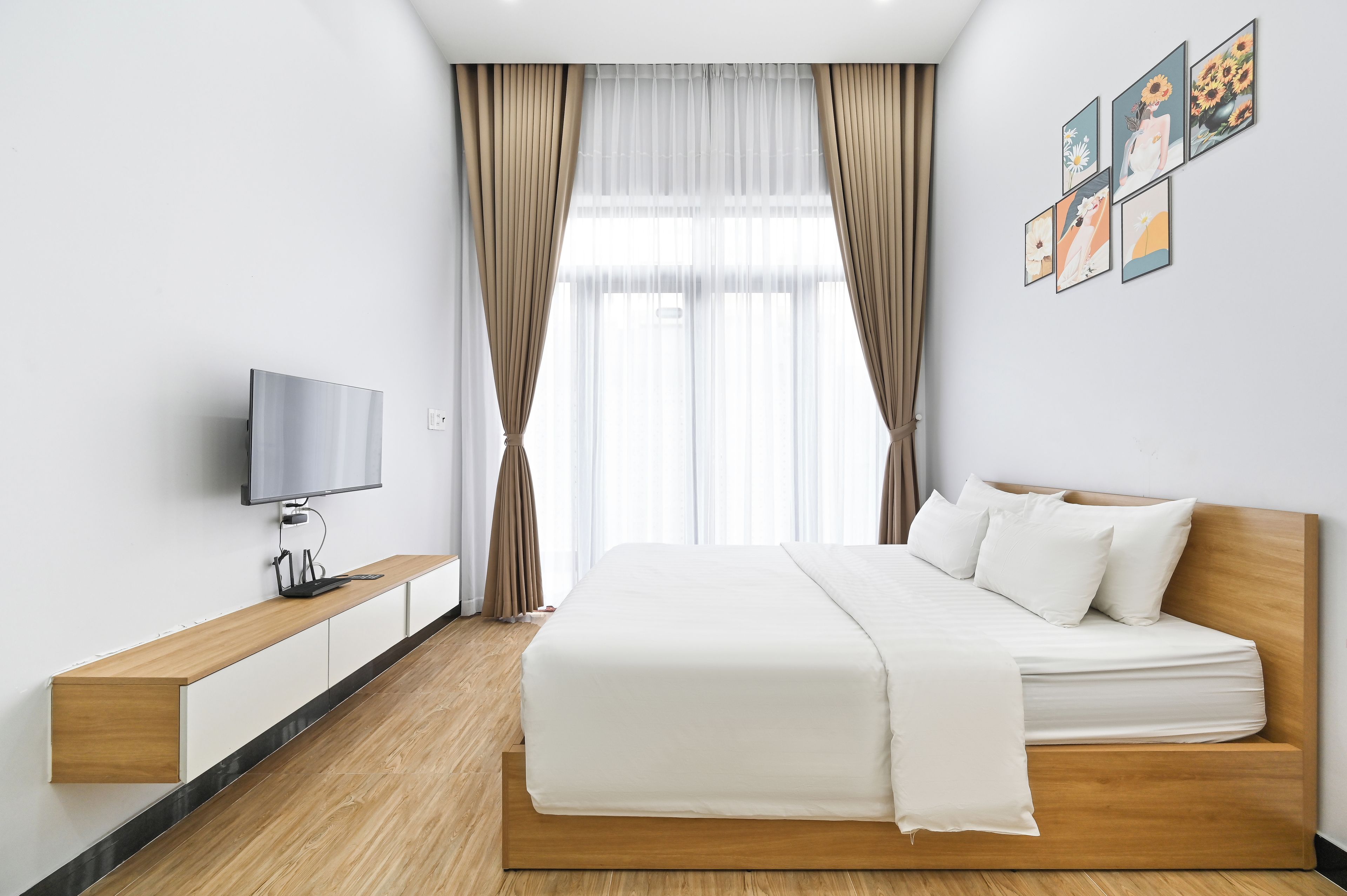 A modern hotel room with a bed, a TV, and a wooden bedside table.