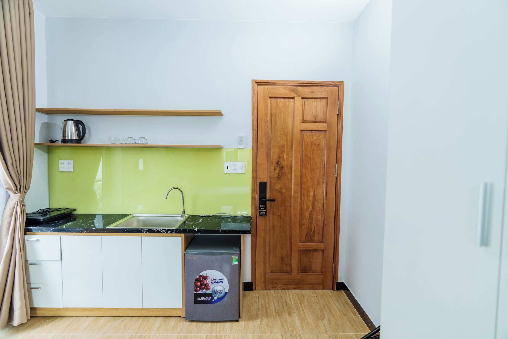 Una cocina compacta con un lavamanos, una cafetera y un refrigerador.