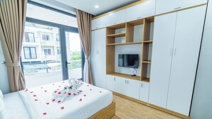 Een hotelkamer met een bed, een televisie bevestigd aan een houten plank en uitzicht op het balkon.