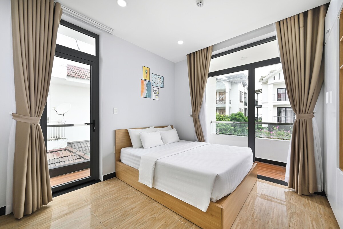 Una habitación de hotel con cama, cortinas, ventana y balcón.