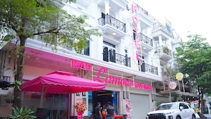 Un hôtel avec un auvent rose et une enseigne sur laquelle on peut lire « Hôtel Lamour ».