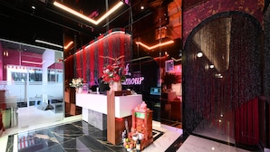Un hall d’accueil d’hôtel au design moderne, avec un sol en marbre, un comptoir d’accueil et une fontaine décorative.