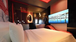 Une chambre d’hôtel moderne avec un grand lit, un téléviseur fixé au mur et une vue sur une jetée.