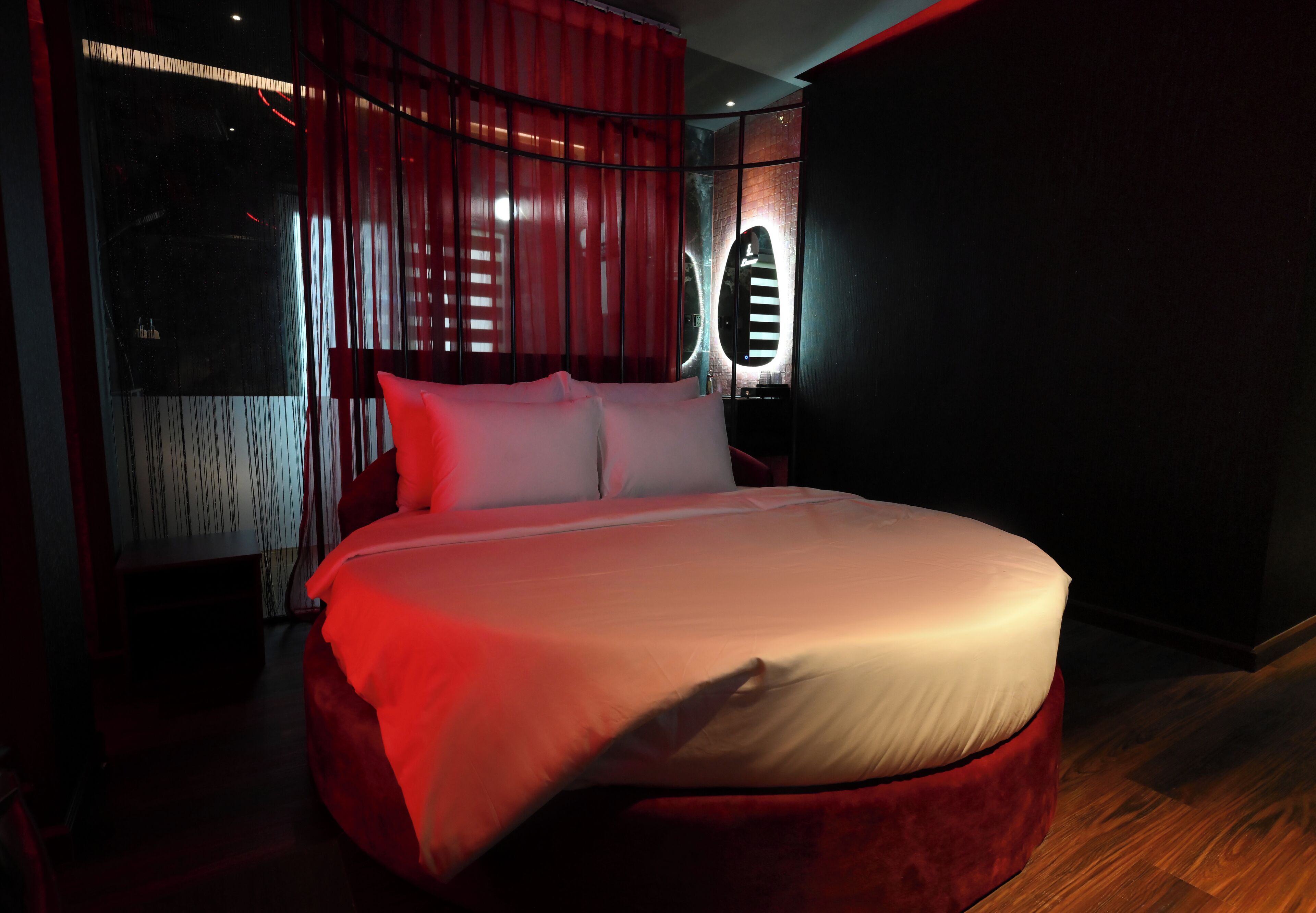 A modern bedroom with a large bed, red curtains, and a unique circular light fixture.
