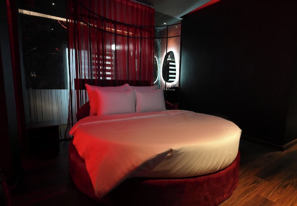 A modern bedroom with a large bed, red curtains, and a unique circular light fixture. - Hotel Lamour (Ho Chi Minh City)