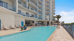Ein Hotelpoolbereich mit einem klaren blauen Pool, Liegestühlen und einer Palme.