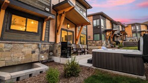 Una moderna casa a più piani con facciata in pietra, una vasca idromassaggio e area relax esterna.