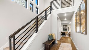 Un interno su più livelli con una scala, una panca e un corridoio che conduce a una zona living.