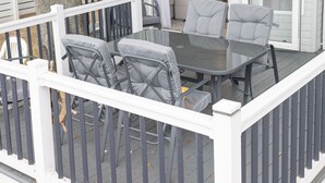 A mobile home with a deck, two grey cushioned chairs, a glass table, and a white railing. - Paddington's Place – A Luxurious Seaside Escape in Mudeford (Christchurch)