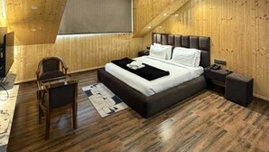 A bedroom with a sloped ceiling, a bed, a desk, and a chair. - Hill Top Heaven By Elvora Hotels & Resorts (Kasauli)