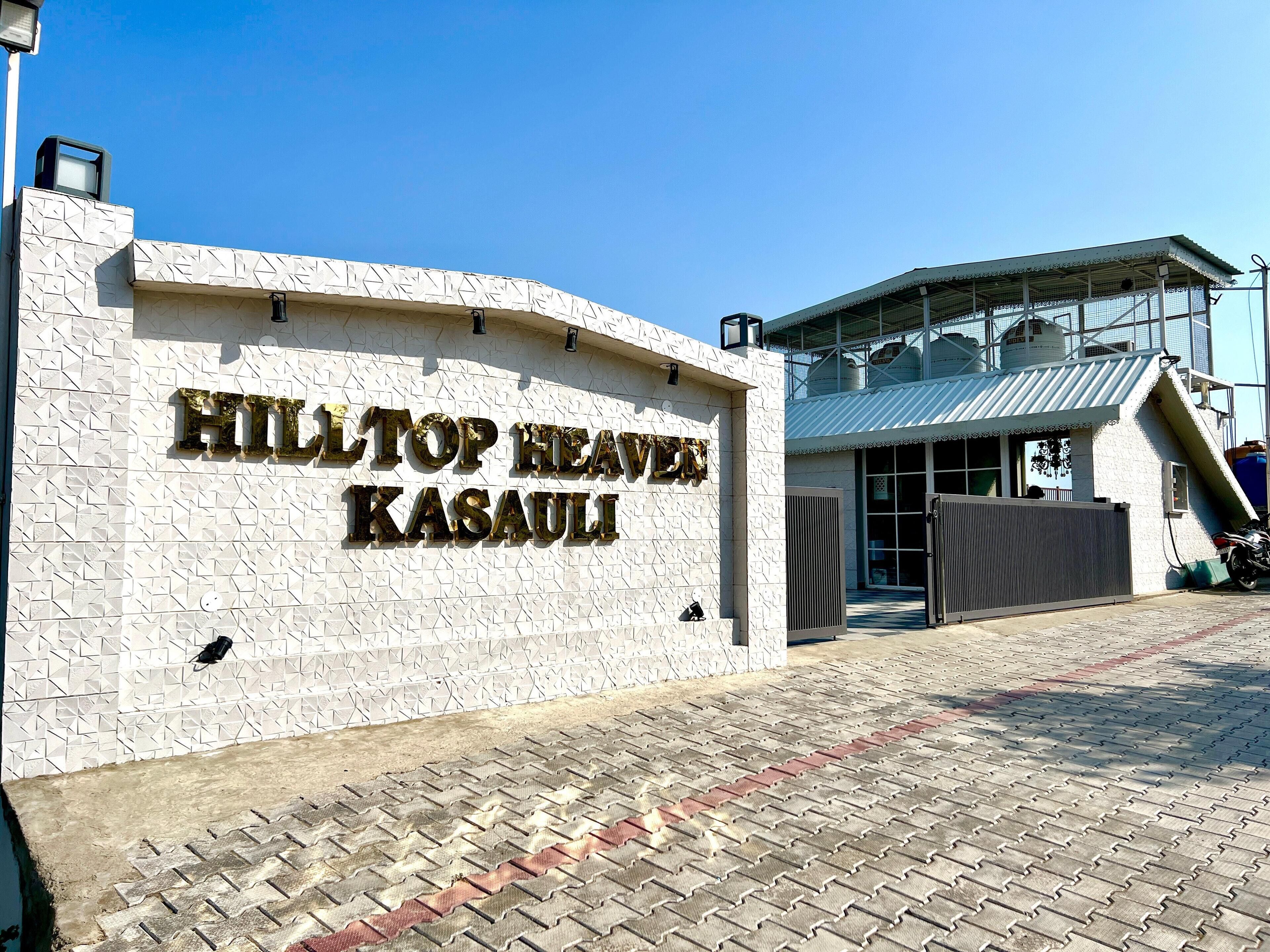 Entrada de un hotel con un letrero que dice 'HILLTOP HEAVEN KASAULI'.