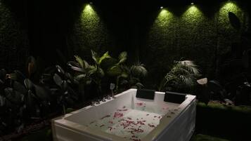 Um quarto de spa com uma banheira grande, plantas verdes e um ventilador de teto.
