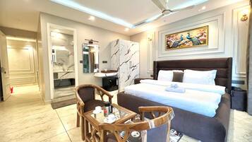 A hotel room with a bed, a desk with a chair, a coffee machine, and a painting on the wall.