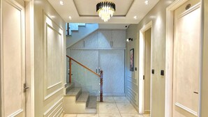 A hallway with a marble floor, a staircase with a striped wall, and a chandelier. - Hill Top Heaven By Elvora Hotels & Resorts (Kasauli)