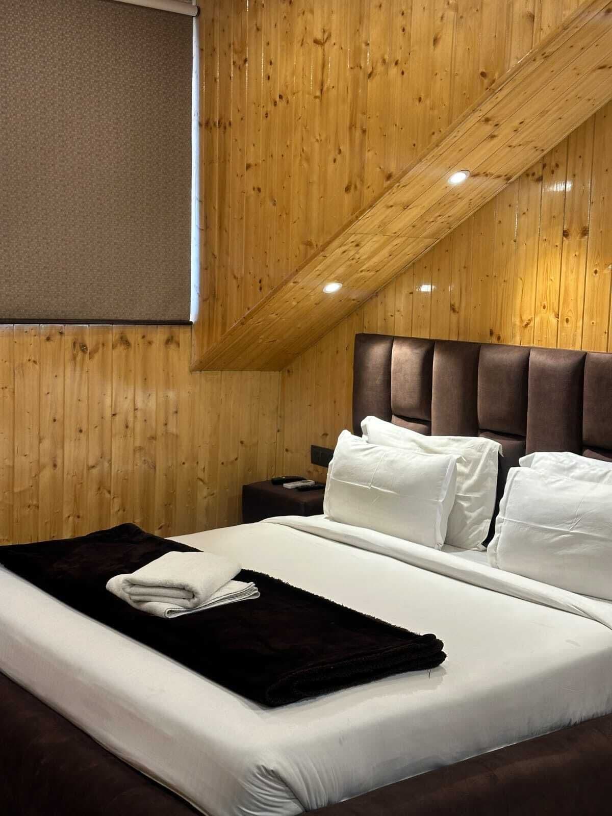 A wooden-paneled room with a bed, pillows, a blanket, and a nightstand.