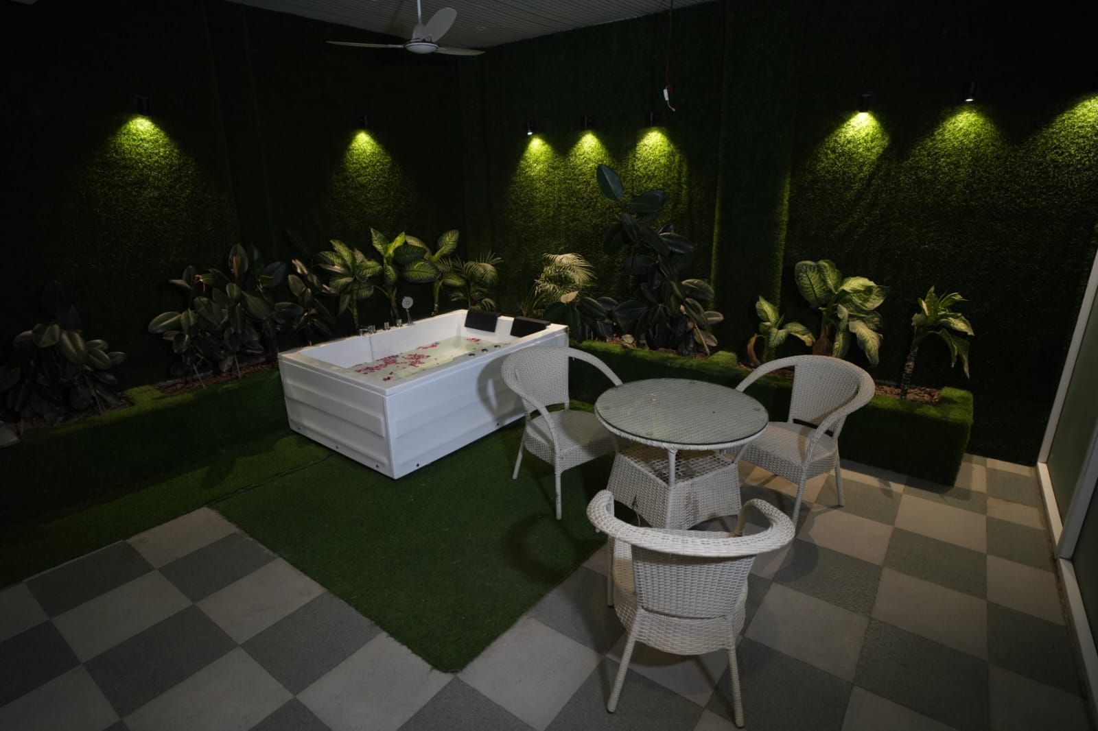 Un área de spa con una bañera blanca, dos sillas de mimbre y una pequeña mesa redonda.