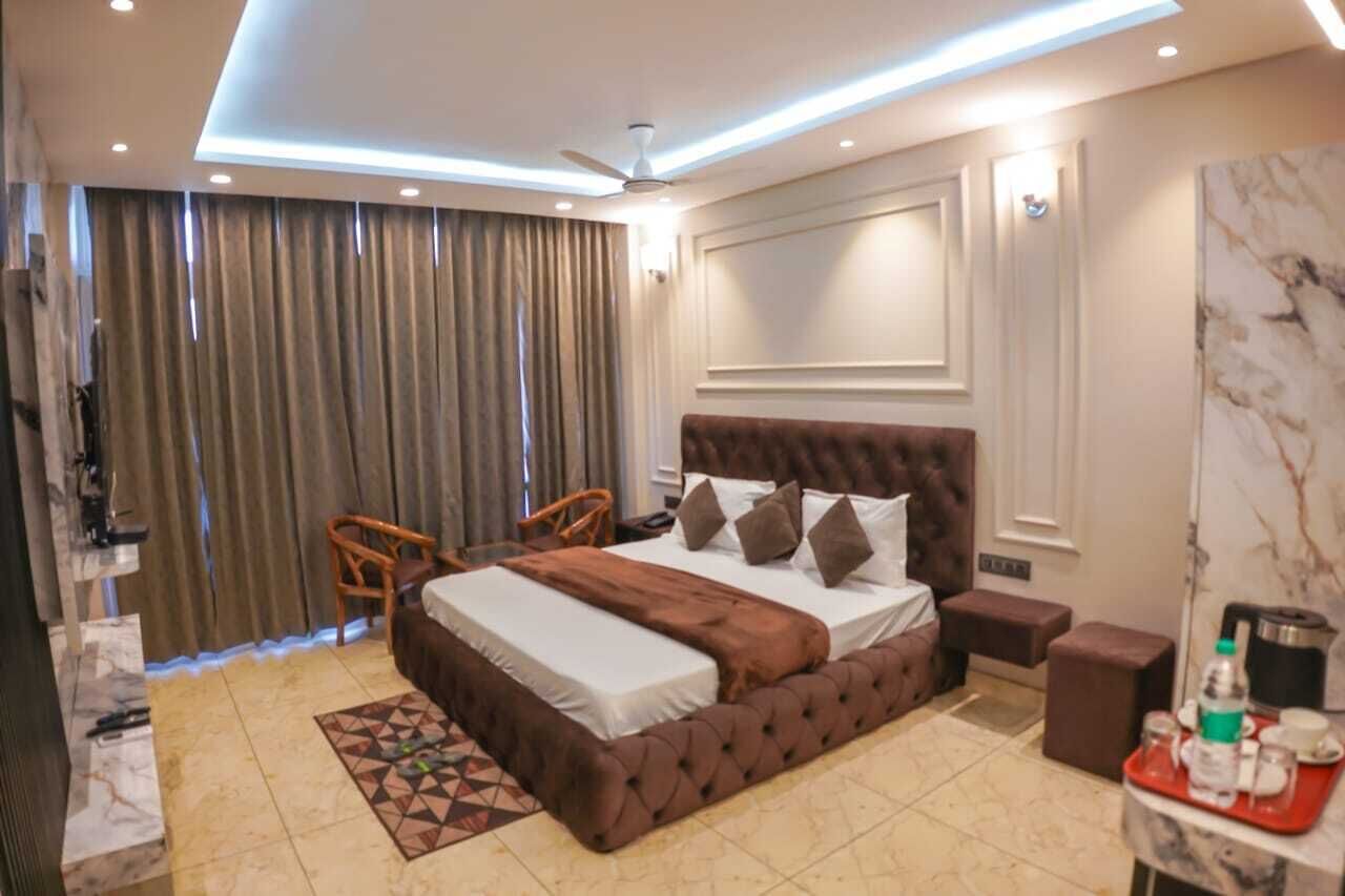 Un dormitorio con una cama grande, un ventilador de techo, una mesita con bandeja y una ventana con cortinas.