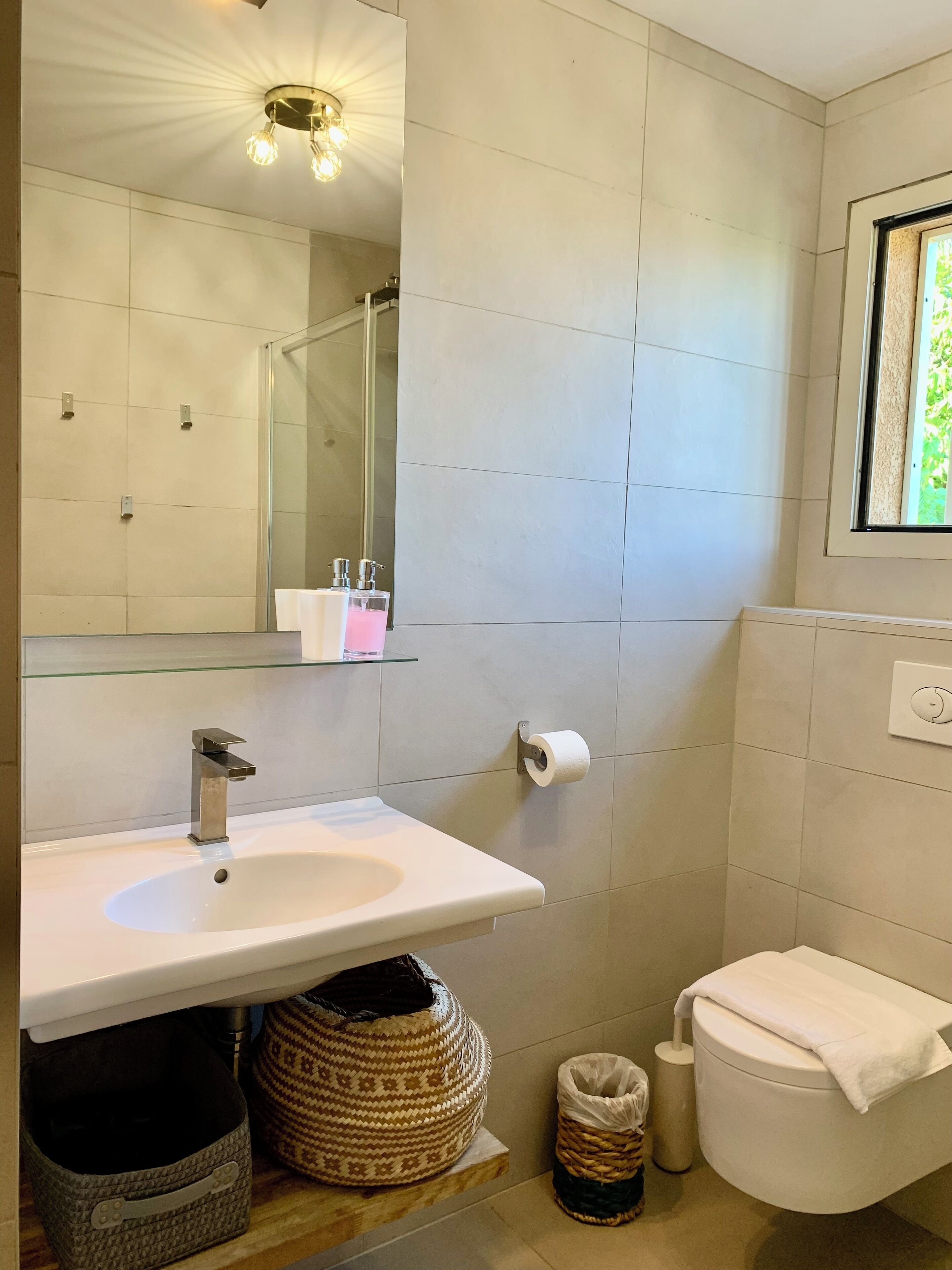 A modern bathroom with a white sink, mirror, and toilet.