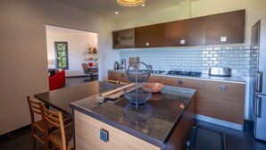 A modern kitchen with a central island, wooden cabinets, a gas stove, and a built-in oven. - residence Guddelmoni (Propriano)