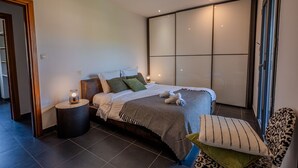 A modern bedroom with a large bed, bedside tables, a chair, and a sliding glass door. - residence Guddelmoni (Propriano)