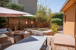 Eine Terrasse im Freien mit Tisch, Stühlen, einem Whirlpool und verschiedenen Pflanzen.