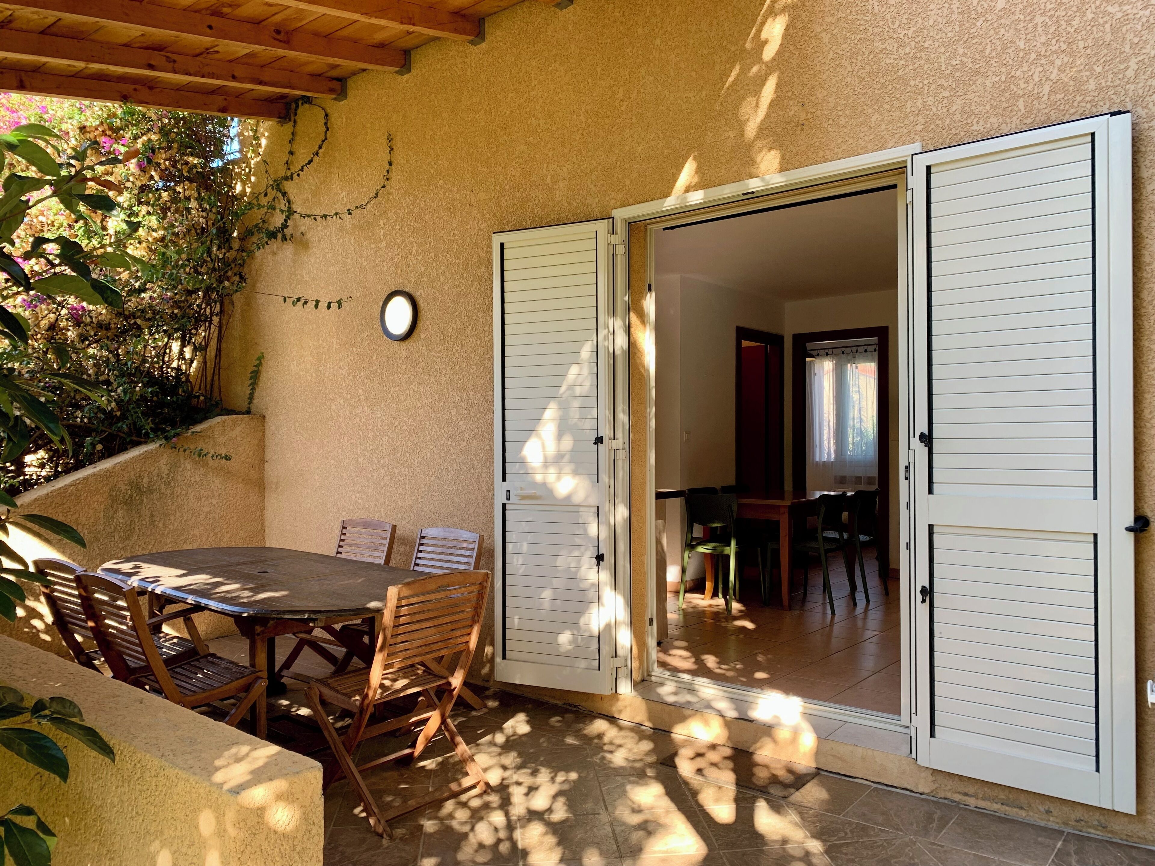 A patio with a table and chairs, a wooden ceiling, and a wall-mounted clock.