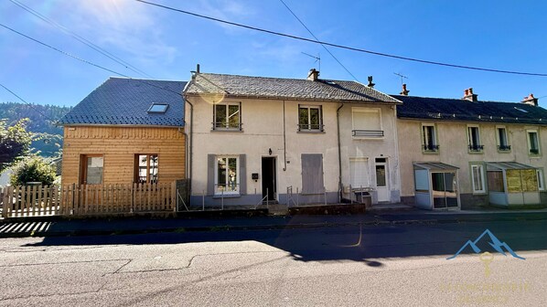 Eine Reihe von dreigeschossigen Gebäuden mit Holzzaun, einer gepflasterten Straße und blauem Himmel.