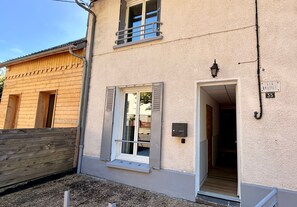 A building with a wooden facade, a door with a window, and a sign reading "LES BRUMES".