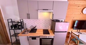 A compact kitchenette with a built-in oven, a refrigerator, and a microwave.