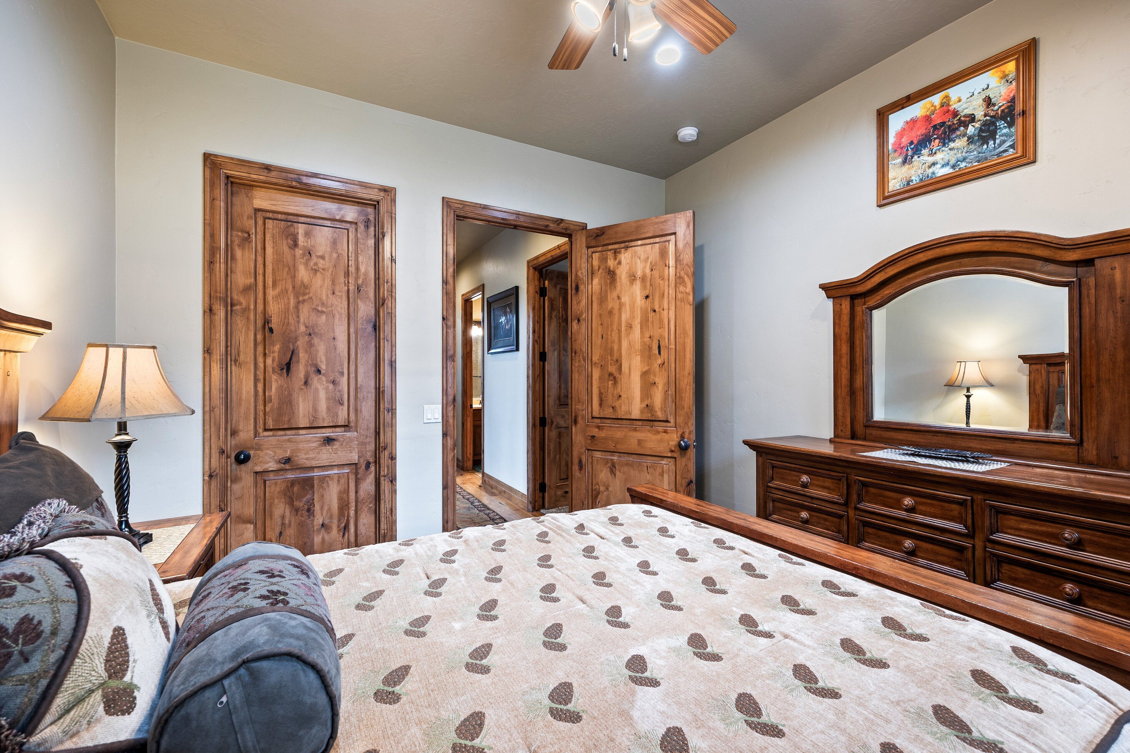 A bedroom with a bed, wooden wardrobe, and a dresser with a mirror.