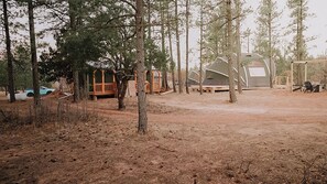 Un camping con varias tiendas en forma de cúpula, una terraza de madera y una mesa de picnic.