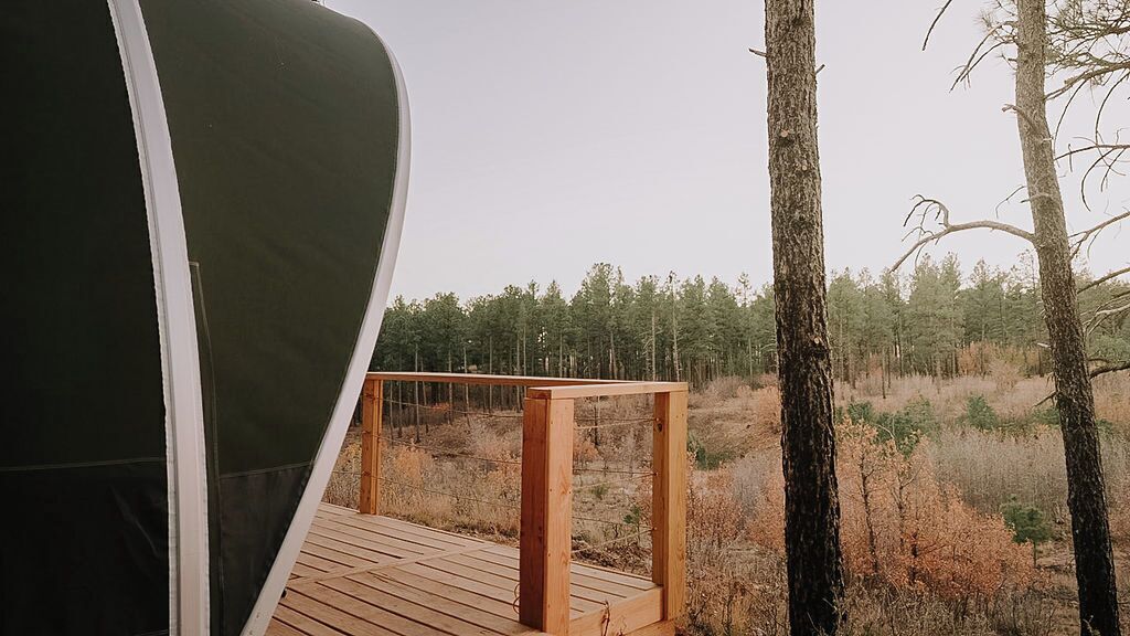 A tent on a wooden deck with a view of a forest.
