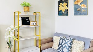 Ein modernes Wohnzimmer mit einer Couch, einem dekorativen Regal, einem kleinen Tisch und Wandbildern.