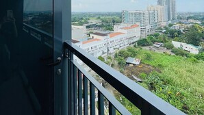 Ein Balkon mit Blick auf eine Stadtlandschaft, einschließlich Gebäude und Grünflächen.