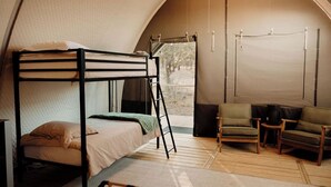 Um quarto tipo tenda aconchegante com beliche, escada, mesa pequena, duas cadeiras e janela com vista para o exterior.