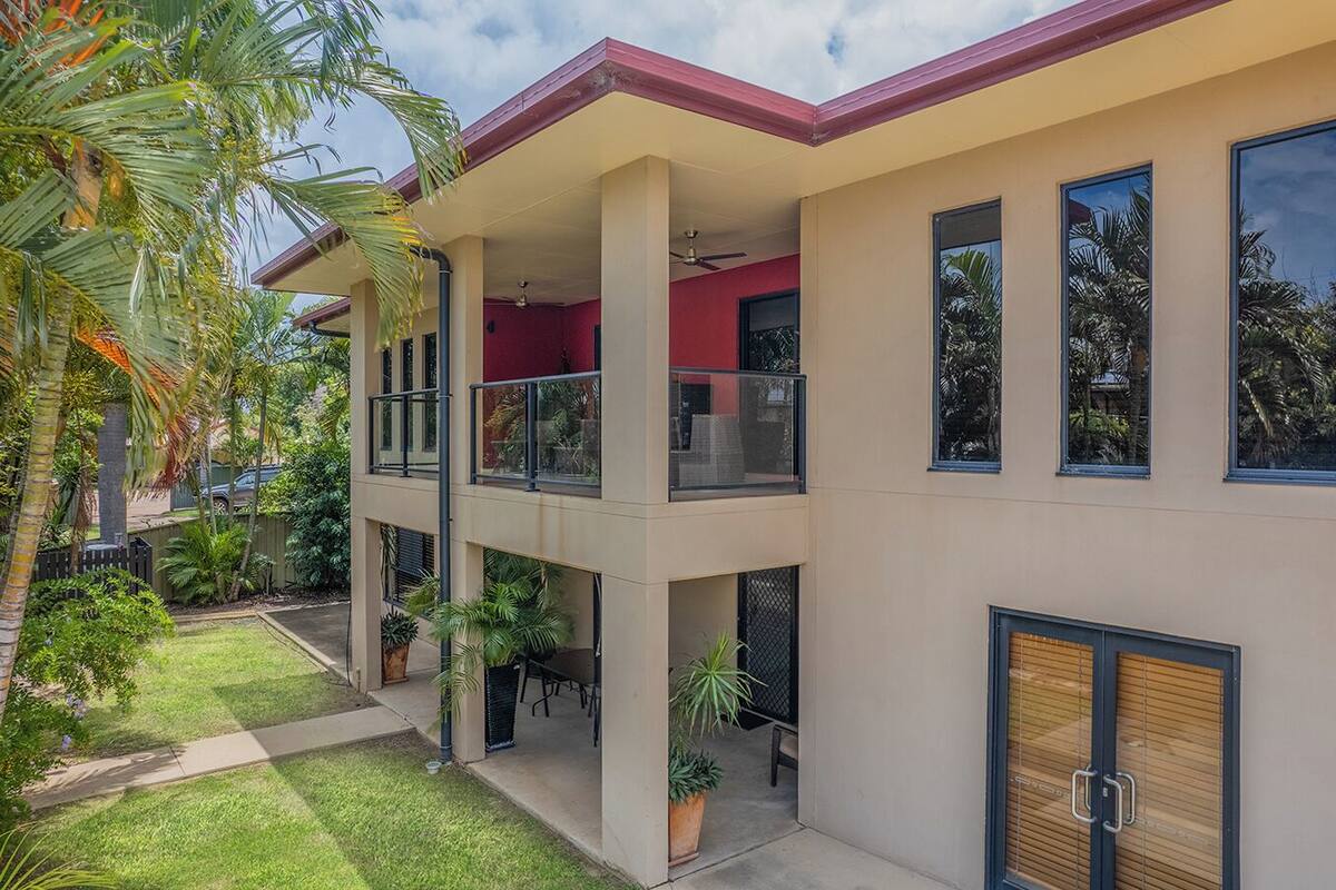 A two-story building with a flat roof, multiple balconies, and large windows.