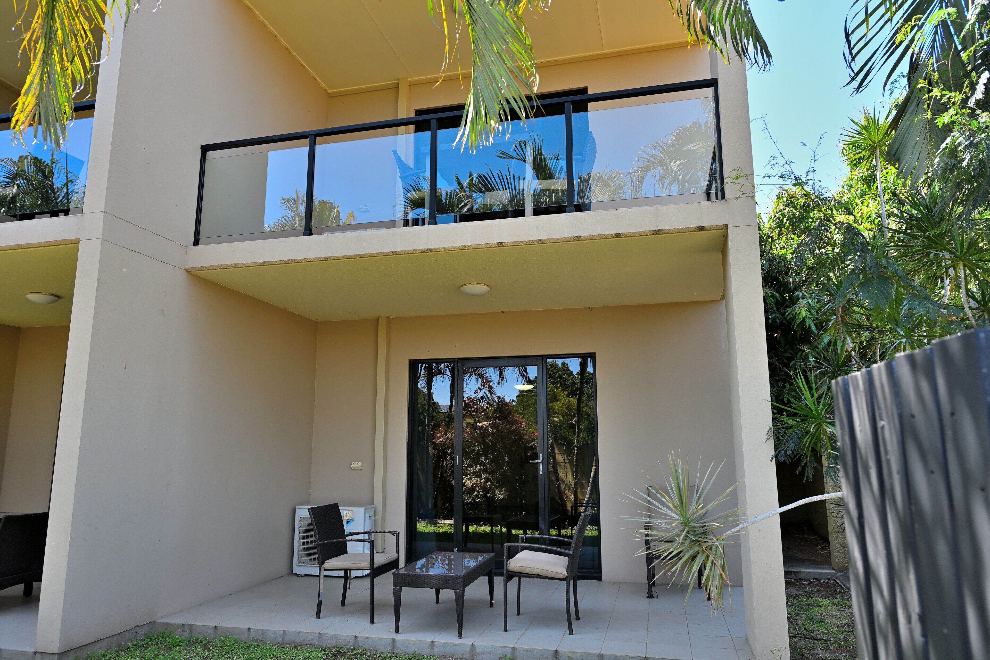 A modern two-story building with a balcony, outdoor seating area, and large glass doors.