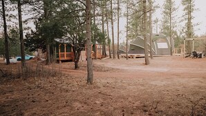 A campsite with several dome-shaped tents, wooden structures, and a dirt ground. - Mountain Stay Under Open Skies (Torreon)