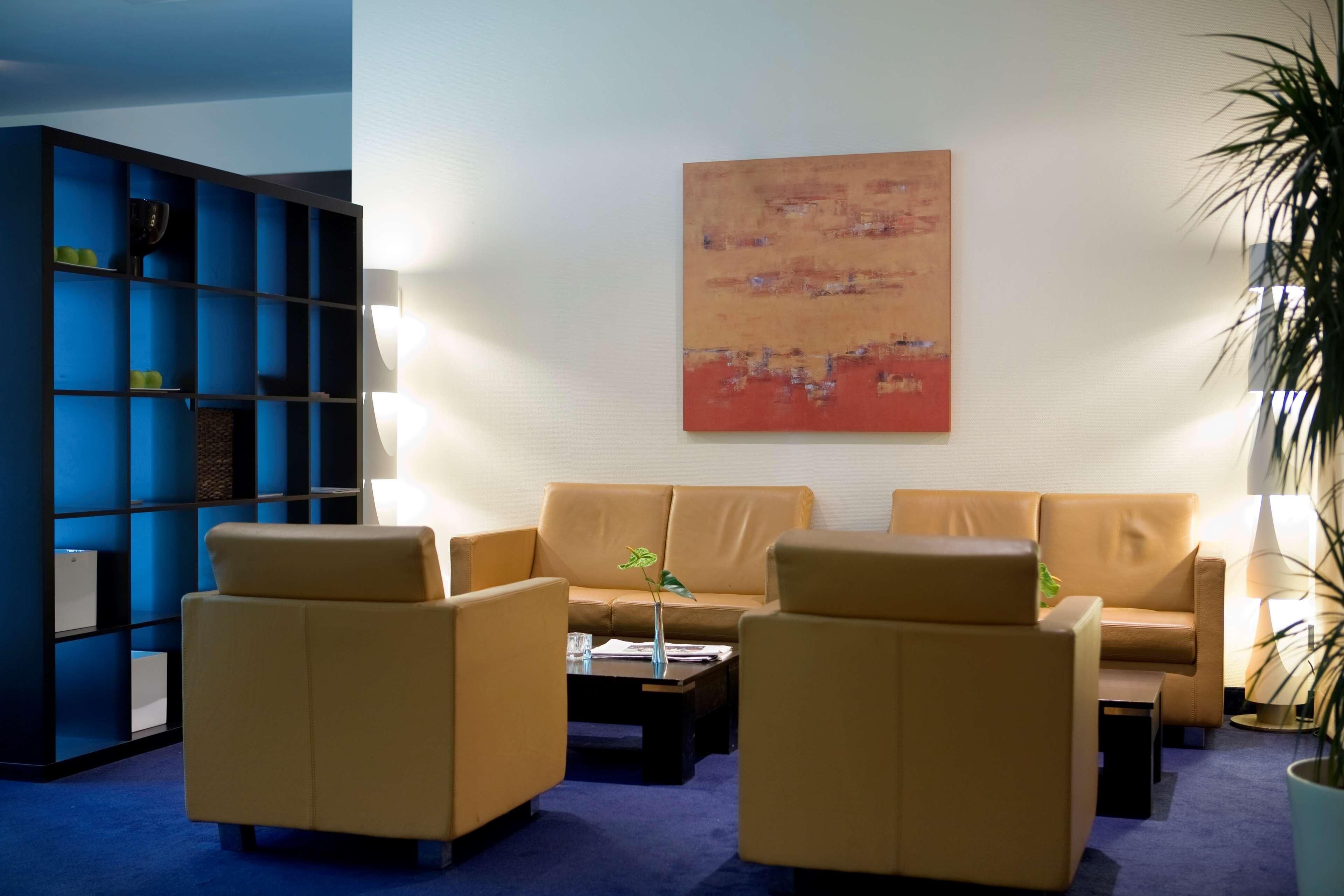 A modern lounge area with leather sofas, a coffee table, and a blue shelving unit.