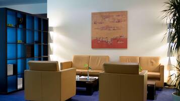 A modern lounge area with leather sofas, a coffee table, and a blue shelving unit.