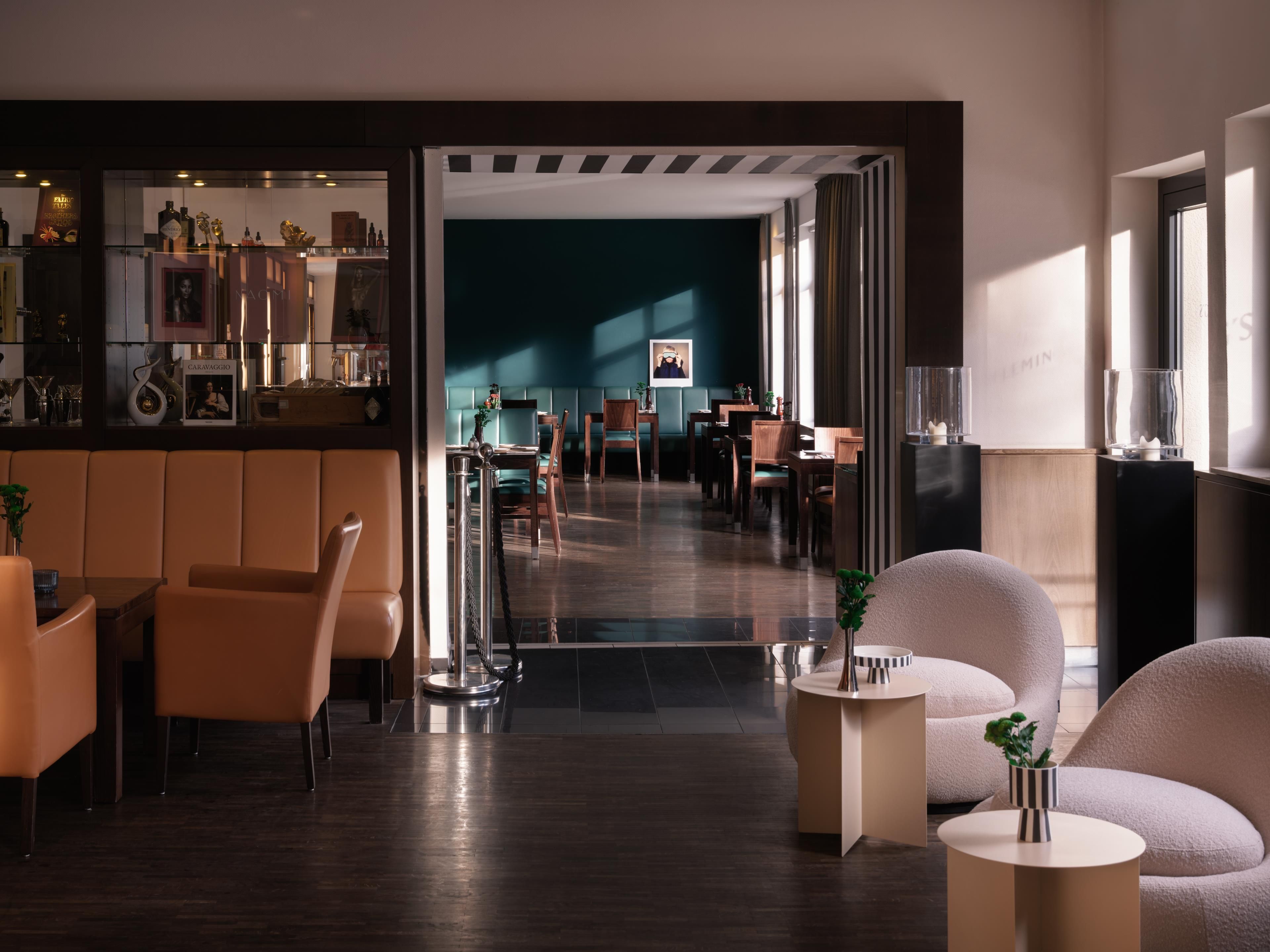 Un interior moderno con una zona de bar, asientos y vistas hacia un comedor.