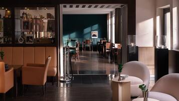 A modern interior with a bar area, seating, and a view into a dining space.