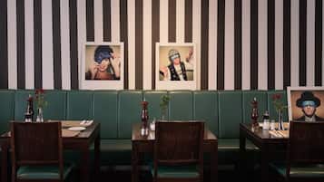 A restaurant with striped walls, green booths, wooden tables, and chairs.