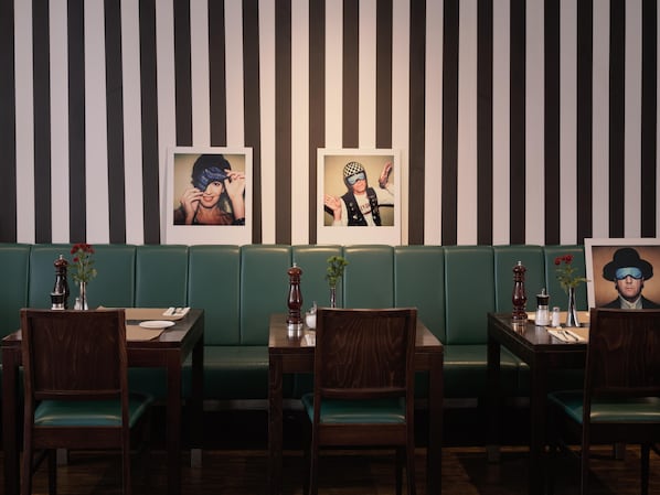 A restaurant with striped walls, green booths, wooden tables, and chairs. - Flemings Hotel München-schwabing (Munich)