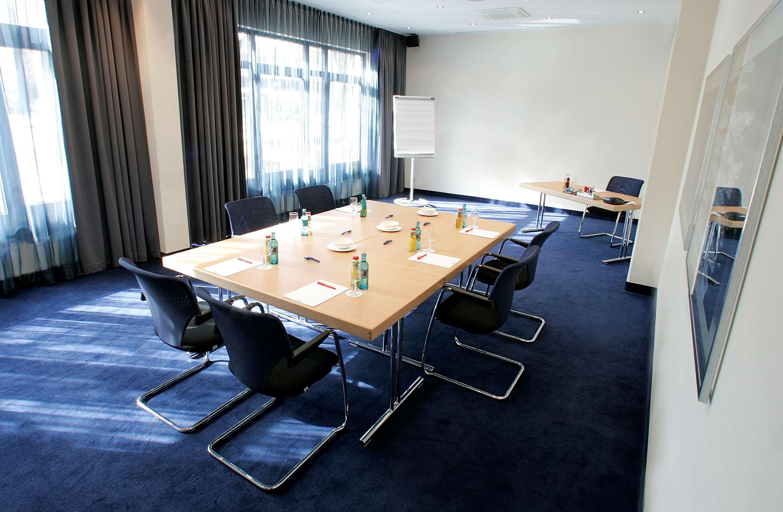 A conference room with a long table, chairs, a whiteboard, and a window with curtains.