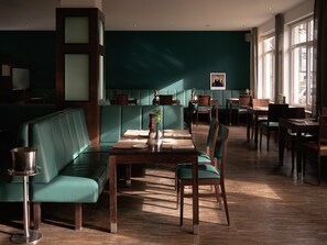 Un restaurant avec des banquettes et des tables, un plancher en bois et une vue sur la rue grâce à de grandes fenêtres.